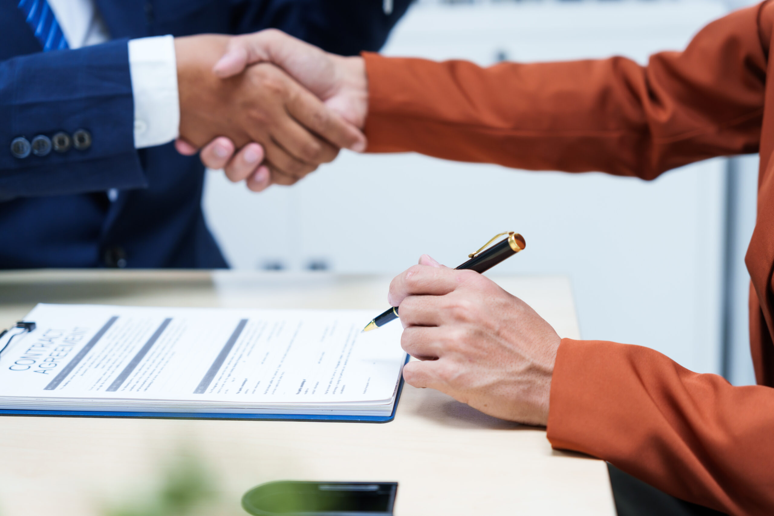 A businessman desk in a sales office sells a condo building customer.They agree to sign a contract